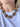 A close-up of a model wearing a chunky link necklace made of brown and amber tortoiseshell-patterned resin with gold-tone metal connectors, paired with a white t-shirt.