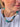 A close-up of a person wearing a beaded necklace made of small round beads in turquoise, dark green, brown, cream, and black, paired with a white t-shirt.