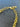 Close-up of a gold chain bracelet with a lobster clasp and a small engraved tag reading YCMI NY, laid on a dark textured surface.