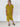 A woman modeling a short-sleeve chartreuse midi dress with a button-down front, standing against a white brick wall.